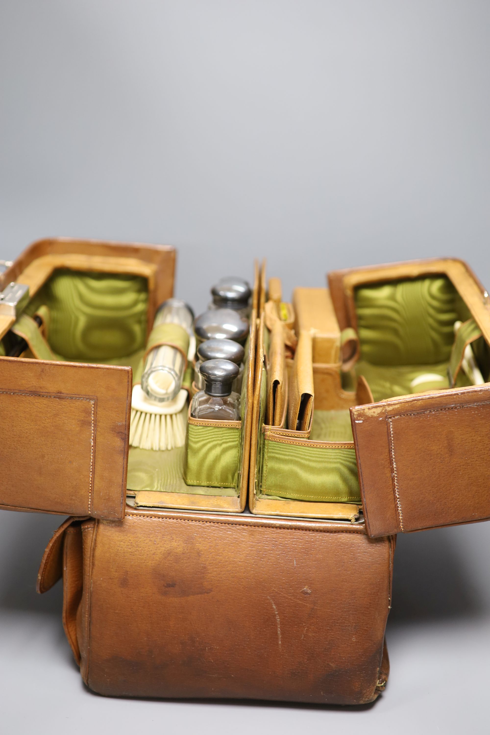 A travelling leather toilet case by H. Greaves, Birmingham, with six silver mounted glass toilet jars, Birmingham and London, 1897,